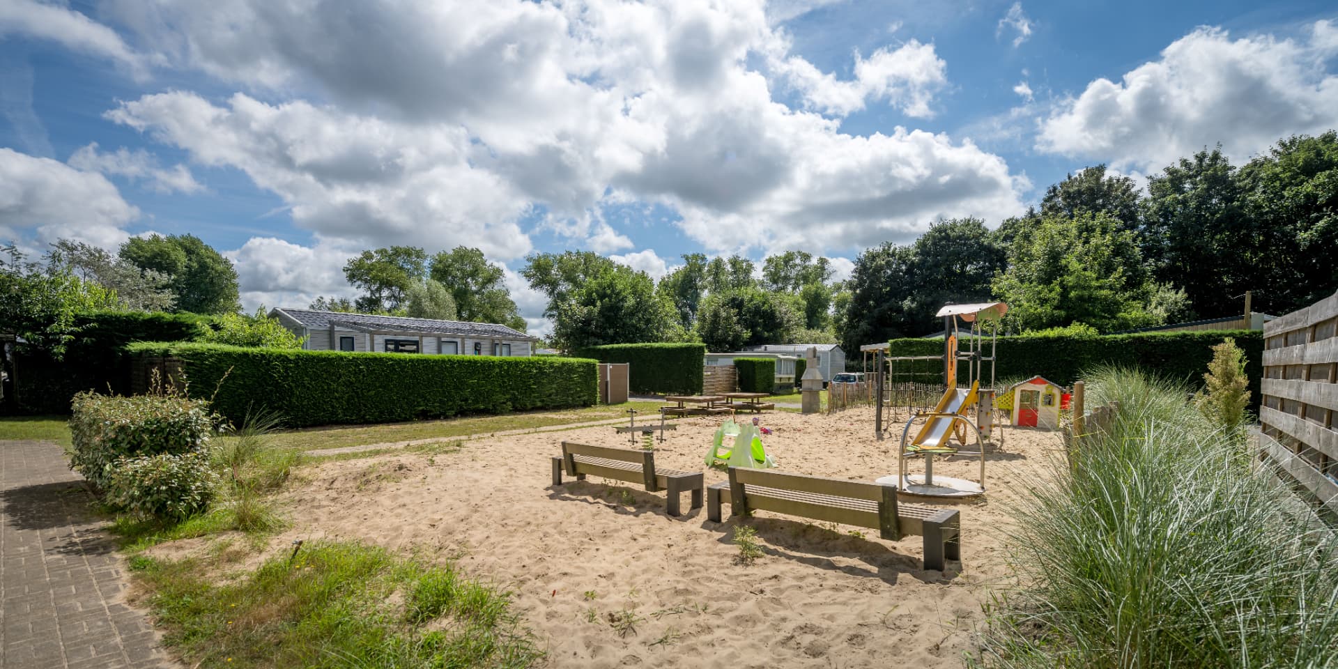 Speelplein met zandbak, glijbaan en banken op het park